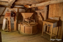 The water mill grinding floor. The hopper feeds grain inot the grindstones (in the circular case) which then falls through a chute into a sack.